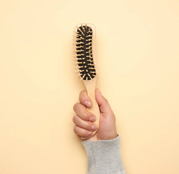 female hand holding a wooden comb, close up