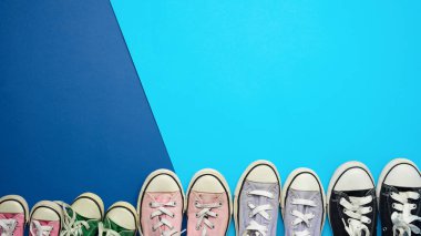 mavi arka plan, üst görünüm, konsept, aile ve takım, arkadaşlık, kopyalama alanı üzerinde farklı boyutlarda çok renkli iyi giyimli tekstil spor ayakkabıları