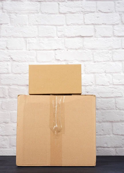 rectangular box made of brown corrugated cardboard on a white brick wall background, close up