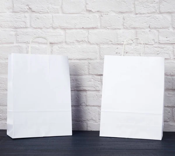 white paper bag with handles on white brick wall background, environmental material, zero waste