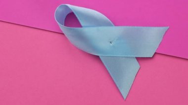 Pembe bir zemin üzerine sarılı mavi ipek kurdele, prostat kanseri farkındalığı sembolü, kapatın.