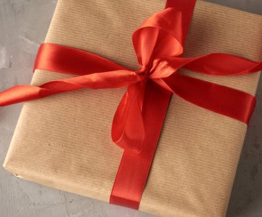 Kahverengi kraft kağıt zemin üzerinde kırmızı ipek kurdeleden yapılmış düğümlü fiyonk, şenlikli zemin