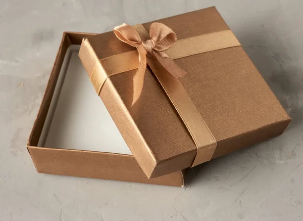 open golden square gift box on gray background, top view