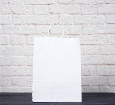 Beyaz tuğla duvar zemininde beyaz kağıt çanta, çevresel malzeme, sıfır atık 