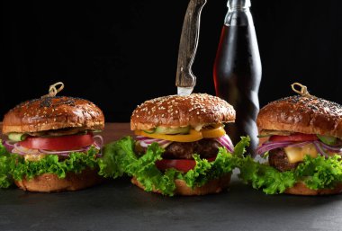 Lezzetli hamburgerler, kızarmış sığır pirzolası, domates, marul ve soğan, susamlı beyaz buğday unlu çörek. Tahtadaki fast food.