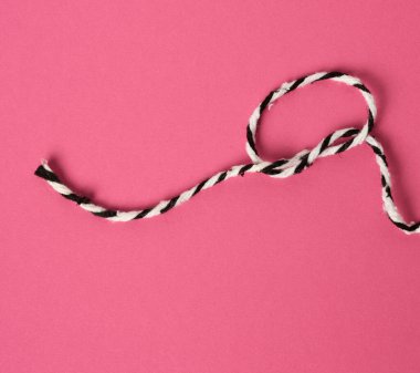 Pembe arka planda beyaz-siyah ip. Döngü şeklinde bükülmüş. Yaklaş.