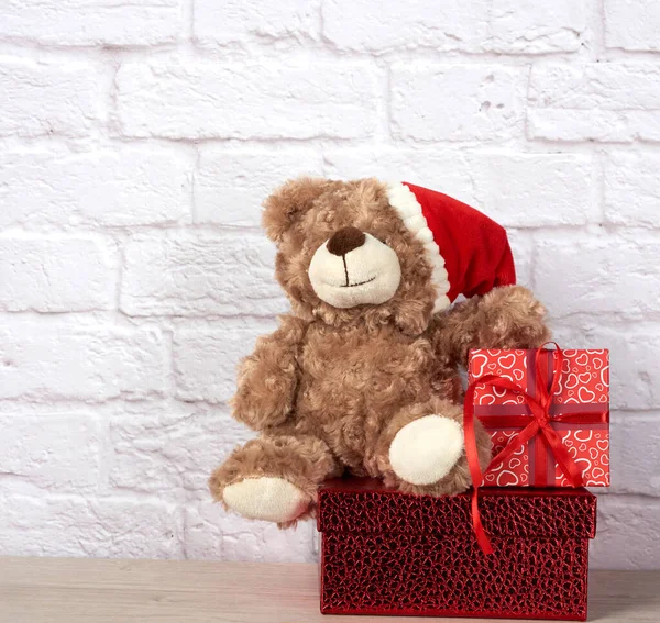 teddy bear in santa claus hat and box tied with red ribbon, christmas backdrop