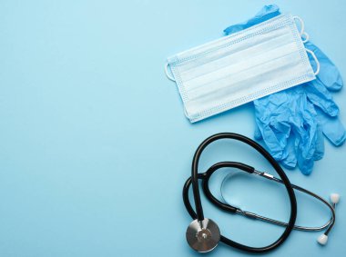 Mavi arka planda mavi lateks eldivenler ve tek kullanımlık maskeler, salgın hastalıklar ve salgınlar için hijyen ve virüs koruma aksesuarları.
