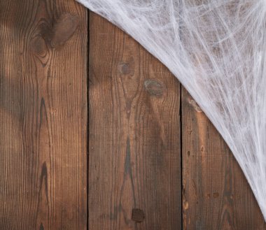 Kompozisyonun köşesinde beyaz örümcek ağı, eski tahtalardan gri ahşap arka plan, Cadılar Bayramı için arkaplan, kopyalama alanı