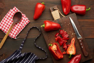 Tahtada dilimlenmiş kırmızı biber, kahverengi ahşap masa, üst manzara.