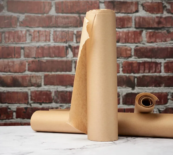 rolls of brown parchment paper on a white table, brown brick wall