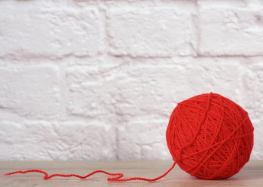 Beyaz tuğla duvar zemininde yün iplikli kırmızı top, kapat