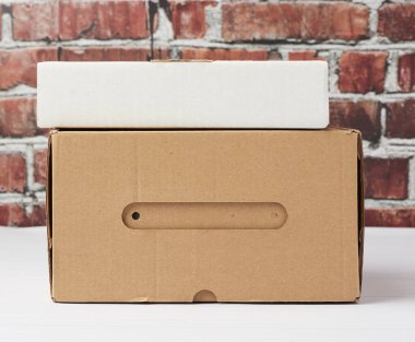 Kahverengi bükülmüş kartondan yapılmış dikdörtgen kutu kahverengi tuğladan bir arka planda, kapat