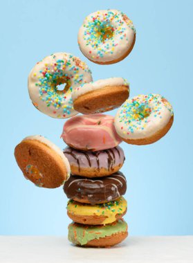 Masanın üzerinde jöleli çörekler var. Etraflarında uçuşan beyaz çörekler.