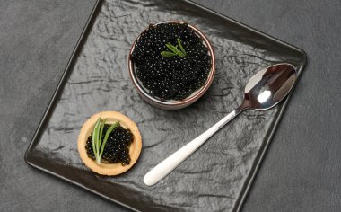 Yuvarlak tart ve siyah kase içinde siyah havyar. Lezzetli bir aperatif.