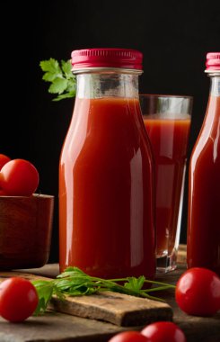 Dolu cam şişe ve koyu arkaplanda domates suyu.