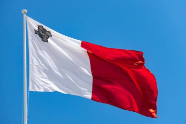 Malta ulusal bayrağının sol üst köşesinde açık mavi gökyüzüne karşı beyaz ve kırmızı bir dizayn bulunan bayrak direğinde dalgalanması.