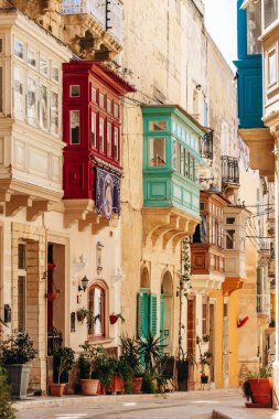 Senglea, Malta - 11 Nisan 2025: Renkli geleneksel Malta ahşap balkonları, kireçtaşı cepheleri, saksı bitkileri ve Senglea eski kasabasındaki tarihi mimarisi ile Picturesque caddesi.