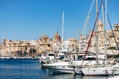 Birgu, Malta - 11 Nisan 2025: Birgu marinasından tarihi Senglea rıhtımına kilise, kubbe, ünlü kuleler ve Akdeniz kıyısı boyunca uzanan yatlarla bakan panoramik manzara