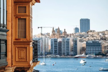 Valletta 'da geleneksel ahşap Malta balkonları modern gökyüzüne doğru panoramik manzaralı ve limanın karşısındaki Sliema' nın deniz manzaralı, su üzerinde tekneleri olan..