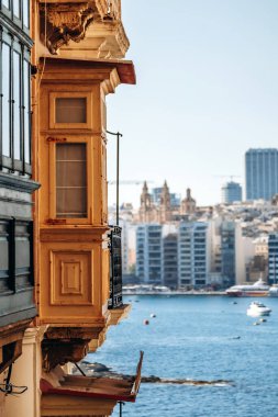 Valletta 'da geleneksel ahşap Malta balkonları modern gökyüzüne doğru panoramik manzaralı ve limanın karşısındaki Sliema' nın deniz manzaralı, su üzerinde tekneleri olan..