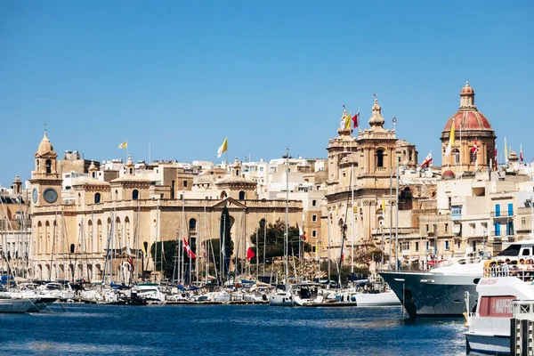 Birgu, Malta - 11 Nisan 2025: Birgu marinasından tarihi Senglea rıhtımına kilise, kubbe, ünlü kuleler ve Akdeniz kıyısı boyunca uzanan yatlarla bakan panoramik manzara