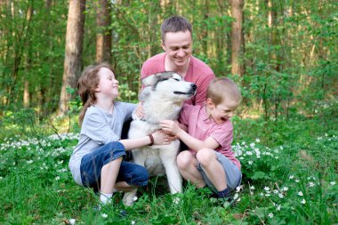 Baba ve iki oğlu ile onların köpek malamute ormandaki bir yolda