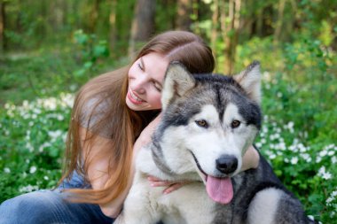 Kızıl saçlı Genç kadın onun köpek malamute ormanda bir yürüyüş ile çalış