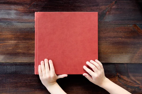 kid holding hands on brown leather covered wedding album or book. Wedding book. Top view