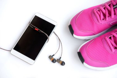 Kavram çalıştırın. Kadınlar, telefon ve kulaklık beyaz bir arka plan üzerinde pembe koşu ayakkabıları. Üstten görünüm. 