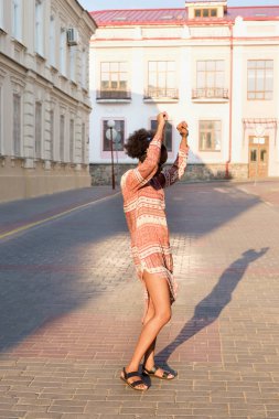 Siyah afroamerican kız akşam kasaba ve kulaklık müzik dinleme bir yürüyüşü vardır. Kız güneş gözlüğü yaz gülümsüyor ve sunset Bulvarında arıyor.