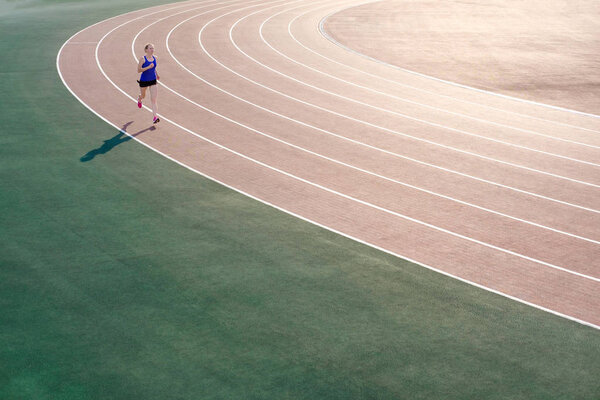 Спорт. Молодая спортсменка в розовых кроссовках бегает по стадиону. Концепция запуска
