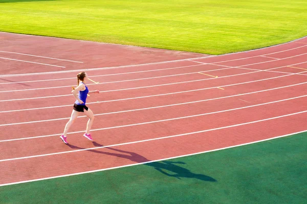 Sport. Athletic young woman in pink sneakers run on running track stadium. Concept run