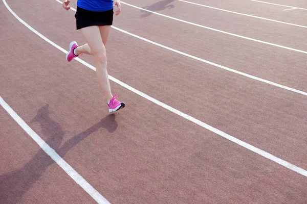 Sport. Athletic young woman in pink sneakers run on running track stadium. Concept run