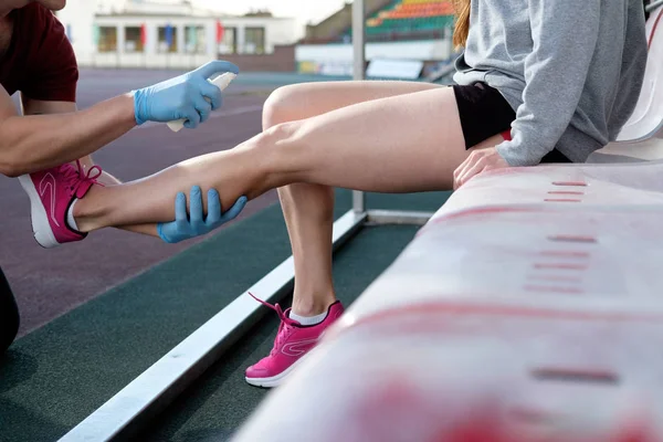 Sports doctor treating injured sportman\'s knee. Sport medicine in action. Injured tenis player\'s or athlete leg is anesthetizing by sport doctor using freezing spray.