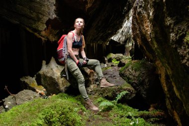Turuncu seyahat sırt çantası ve lightern olan kadın eski kale mağara araştırıyor