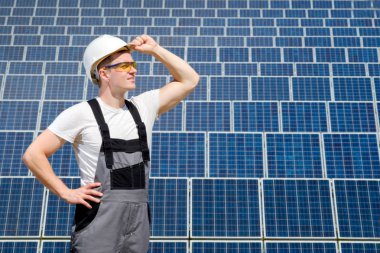 Güneş panelleri mühendis beyaz varil ve güneş panelleri field yakınındaki gri kıyafet stadnding. Sıcak güneşli yaz hava. Uzay kopyalayın. Alternatif enerji türleri. Yenilenebilir ve temiz enerji, teknoloji kavramı.