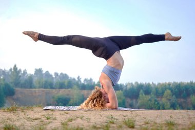 İnce ve sportif Kızıl saçlı kıvırcık kadın veya germe ve pratik yoga açık havada modeli. Kavram aşk yoga. Kavram aşk sabah