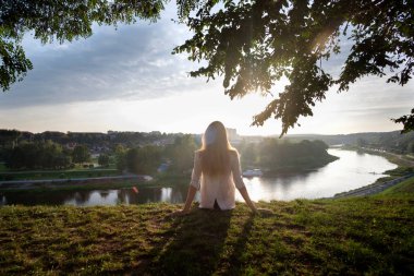 Çimde siting, rahatlatıcı ve nehir manzarayı turist gir. Kavram seyahat, eğlence, turizm.