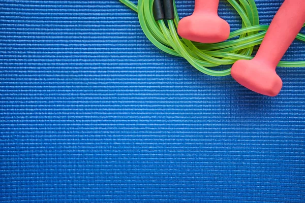 Set of jump rope and dumbeells on the blue background, flat view