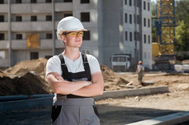 Beyaz koruyucu kask ve iş yarı tulumlar Insaat sitesinde giyen genç yakışıklı çalışkan portresi. Yapı ve Mimarlık kavramı. Adam iş başında.