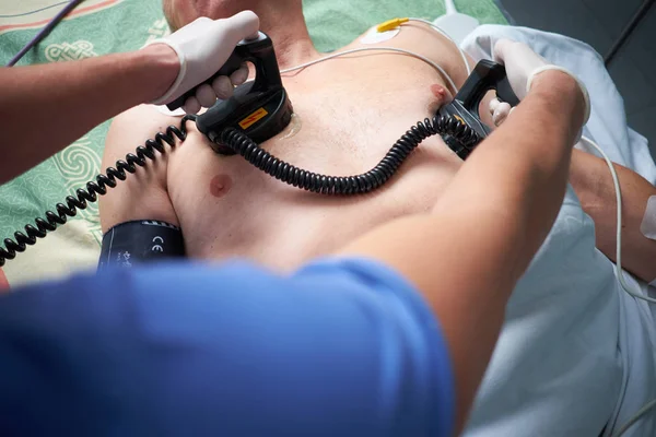 Doctor intensivist performs defibrillation to critical patient