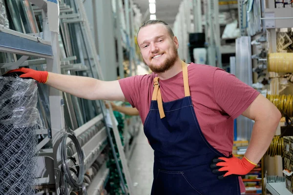 Salesman at construction superstore working with Rabitz. Young attractive cheerful bearded man working on his workplace in building store. People at work concept.