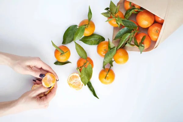 Women\'s hands cleaning tangerine. Orange fresh tangerines with g