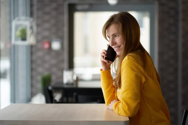 Kafede Oturan Smartphone Ile Konuşurken Sıska Kızıl Saçlı Genç Gülümseyen — Stok fotoğraf