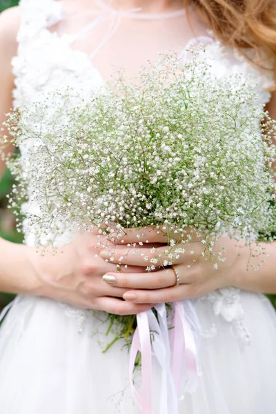 Beautiful light wedding bouquet in the hands of the bride. Close up. Springtime. Wedding floristics.