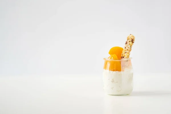 Банка йогурта или творог с мюсли и консервированные абрикосы на белом — стоковое фото