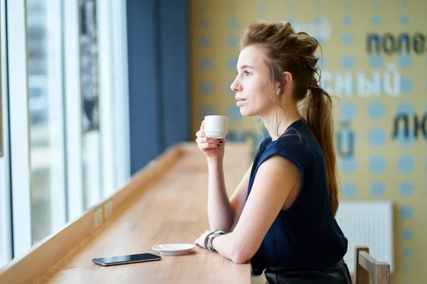 Kızıl saçlı beyaz kız karanlık mavi bluz kafede kahve içme bir — Stok fotoğraf
