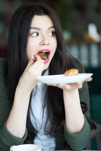 Morena chica comiendo pastel en la cafetería — Foto de Stock