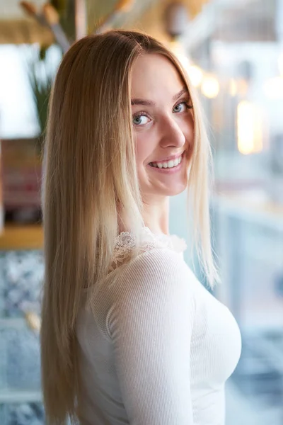 Portrait de jeune fille blonde souriante debout près de la fenêtre — Photo